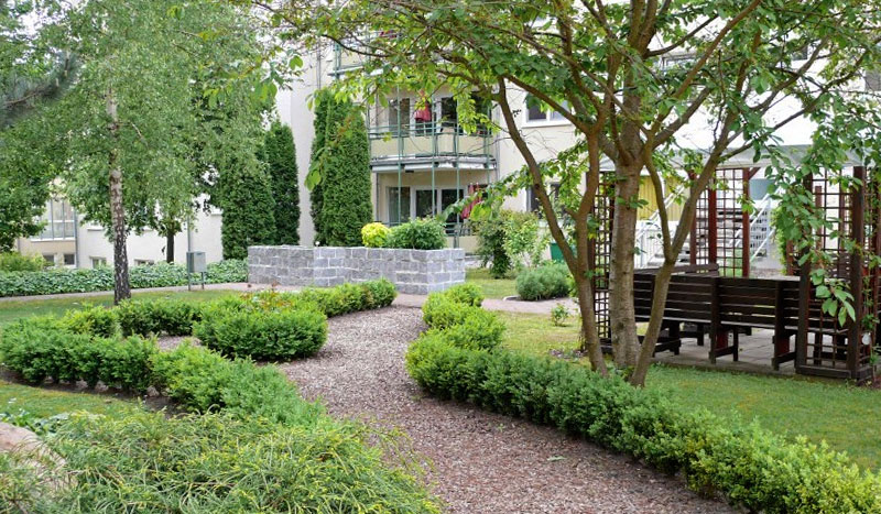 „Garten der Sinne“ des Wohnparks mit angelegten Wegen, Hecken und Sitzbänken